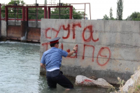В Оше милиционер залез в одежде в воду, чтобы написать на столбе предупреждение гражданам (фото)